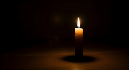 Single candle flame illuminating a dark room, casting a soft glow