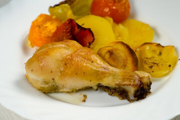 Dish white plate with prepared baked chicken drum sticks with vegetables, close-up. Culinary,...