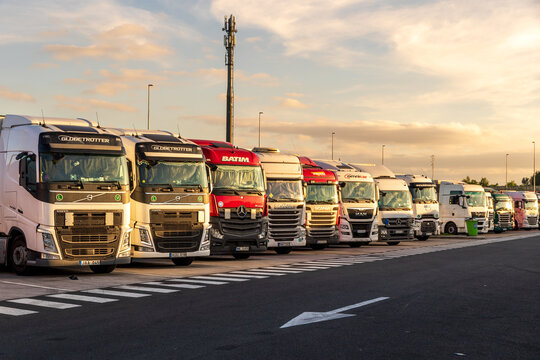 Volvo, Scania, and Mercedes trucks parked at a highway rest stop along the E17 in Belgium, used for overnight parking and driver rest.
