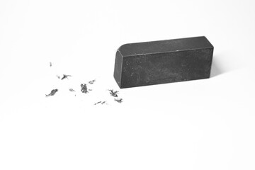 A rectangular eraser with shaved pieces on a white surface, showing signs of use.