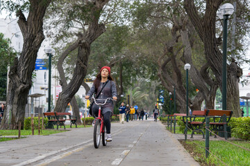 Young woman riding a bicycle through the city park on a cloudy day
