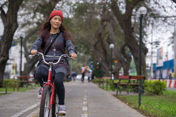 Young woman riding a bicycle through the city park on a cloudy day
