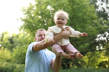 Fototapeta premium Smiling dad and his newborn baby playing outdoors. Happy Father's Day