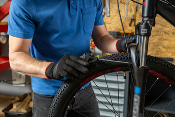 Professional man fixing bike carefully in garage