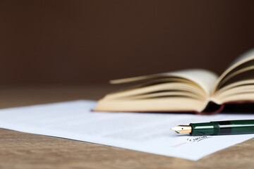 Notary document and fountain pen on wooden table against brown background, selective focus. Space...