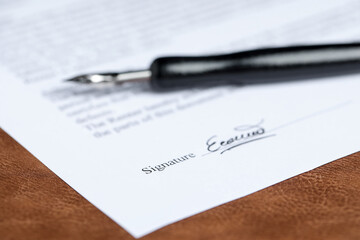 Notary document and fountain pen on brown leather surface, selective focus