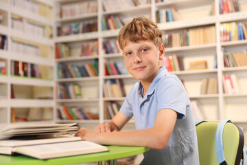 Student with books studying at table in library. Space for text