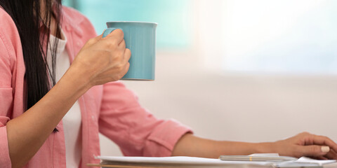 Fototapeta premium Morning Routine. Close-up of young woman holding coffee cup while working.