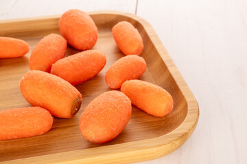 Mini carrots, peeled, on a wooden table, macro.