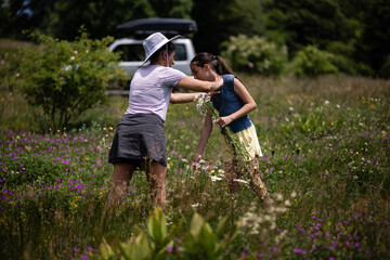 Mother and daughter picking wildflowers in a meadow