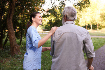 Smiling nurse supporting elderly man in park