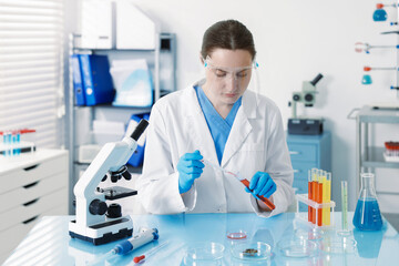 Scientist working with sample in Petri dish at table in laboratory
