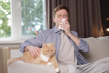 Man suffering from allergy with his cat on sofa at home