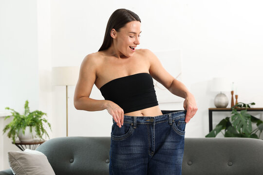 Excited woman wearing old jeans after weight loss at home