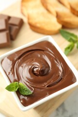 Tasty chocolate spread, pieces, toasts, mint and hazelnuts on white table, closeup