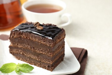 Piece of chocolate cake served with mint and tea on white table, closeup. Space for text