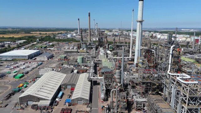 Aerial drone close up view of large industrial Humber petrochemical refinery, fuel storage silos, pipes and pipelines, reactors cooling towers and smoke stacks England UK