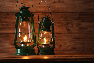 Vintage kerosene lanterns on wooden table, space for text