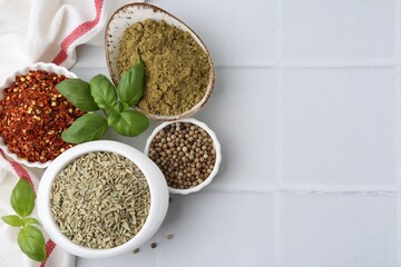 Different aromatic spices on white tiled table, flat lay. Space for text