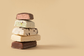 Different whey protein bars with various coatings and sprinkles on beige background. Close up. Copy...