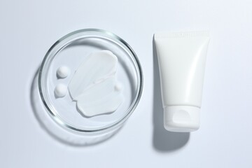 Cosmetic product in Petri dish and tube on white background, top view