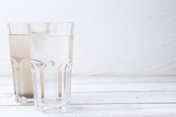 Obraz premium Glasses with clean and dirty water on white wooden table. Space for text