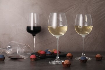 Tasty wine in glasses and truffle bonbons on grey table