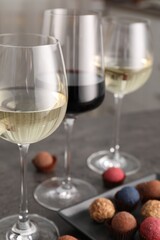 Tasty wine in glasses and truffle bonbons on grey table, closeup