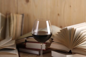 Glass of red wine and open books on table, closeup