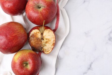 Spoiled apple and good ones on white table, flat lay. Space for text