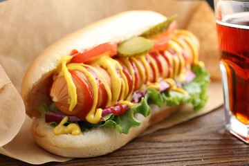 Tasty hot dog and soda drink on wooden table, closeup