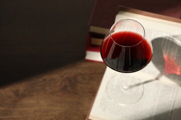 Glass of wine and books on wooden table. Space for text