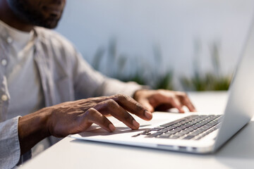 African American man working on laptop typing in office setting