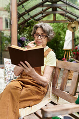 Beautiful senior woman enjoys reading in a tranquil garden during a sunny afternoon