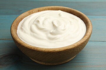Tasty sour cream on blue wooden table, closeup
