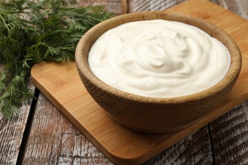 Tasty sour cream with dill on wooden table, closeup
