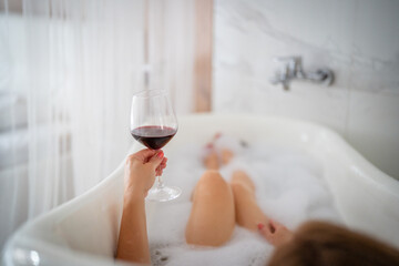 Close-up of female legs with red shoes and glass of wine