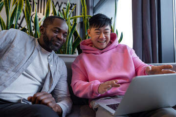 Smiling diverse team members working together on computer in casual office environment