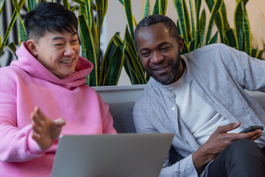 Multiethnic business partners collaborating on laptop in informal workspace