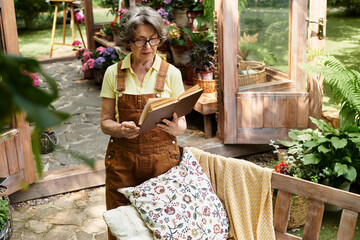 Senior woman enjoying a quiet moment in her vibrant garden while reading a book