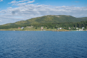 Coastline near Tromso with green forest and typical wooden colorful buildings on the coast, view...