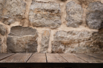 Wooden table mock up with stone wall background. Empty wooden table copy space close up surface...
