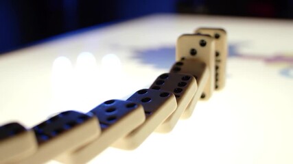 A hand pushes a domino, initiating a chain reaction - Powered by Adobe