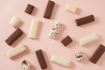 Different whey protein bars with various coatings and sprinkles scoop of protein powder on pink background. Healthy fitness snacks. View from above. Food abstract pattern.