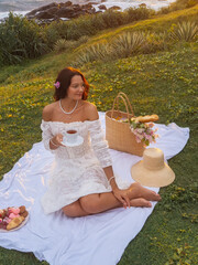 Romantic Woman in White Dress Enjoying Picnic and Tea at Sunset