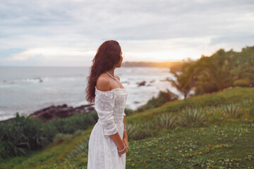 Serene Sunset View of a Woman in White Dress by the Ocean Shore