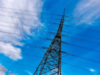 This transmission tower stands tall against a backdrop of blue skies and fluffy clouds, showcasing the vital infrastructure that keeps our communities powered. 