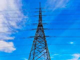 This transmission tower stands tall against a backdrop of blue skies and fluffy clouds, showcasing the vital infrastructure that keeps our communities powered. 