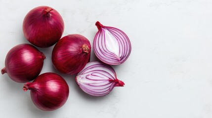 Close-up of whole and sliced red onions arranged neatly on a white marble surface with empty space