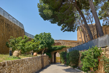 Historic arched stone gateway leading into Denia Castle in Spain, surrounded by ancient walls under...